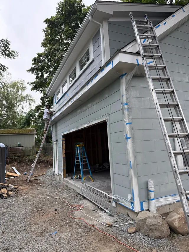 Ladder beside gray exterior siding during work