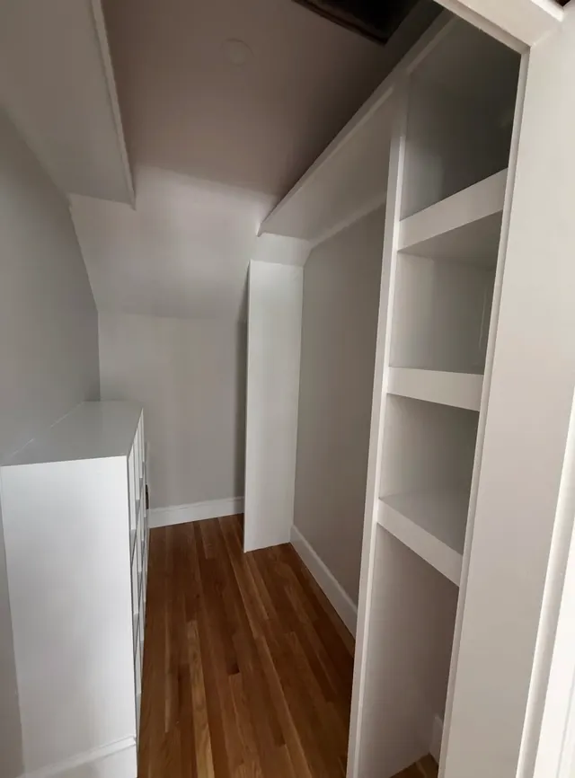 White built-in shelves beside a wood-floored hallway