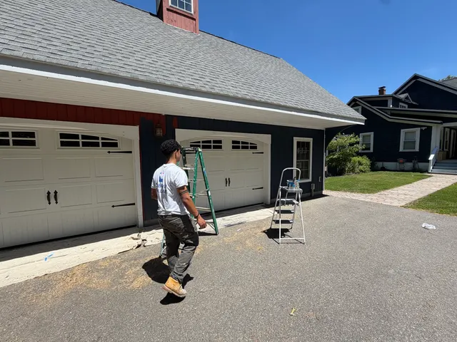 Crew member and equipment beside a detached garage