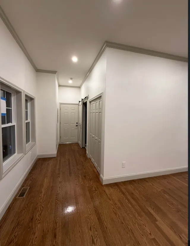 Hallway with light walls, white trim and wood flooring