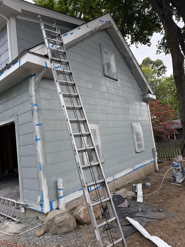 Gray exterior siding and white trim with ladders on site