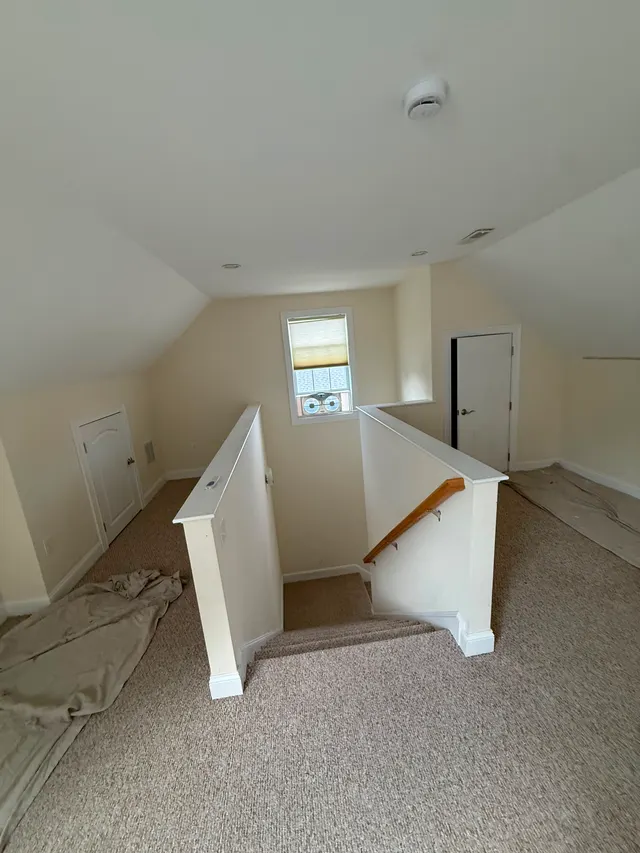 Light-colored attic landing with carpet and a stair railing