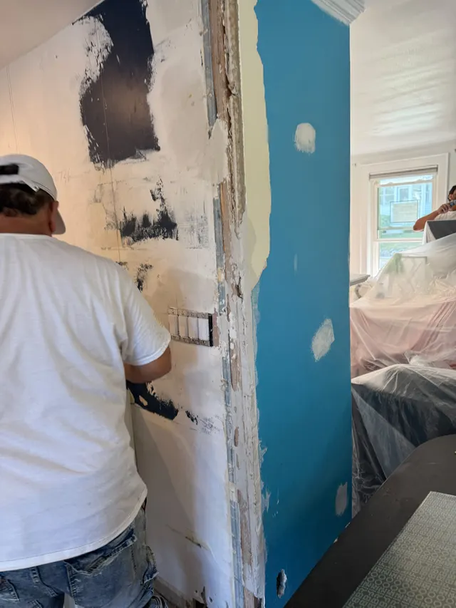 Crew member working on an interior wall with patched areas