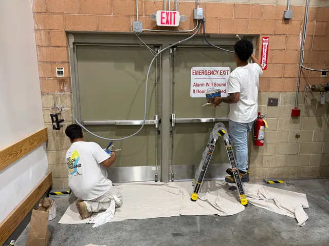Crew working on walls beside commercial entrance doors