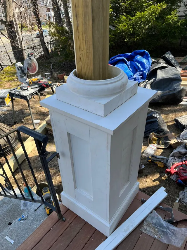 White porch column base beside a wood deck