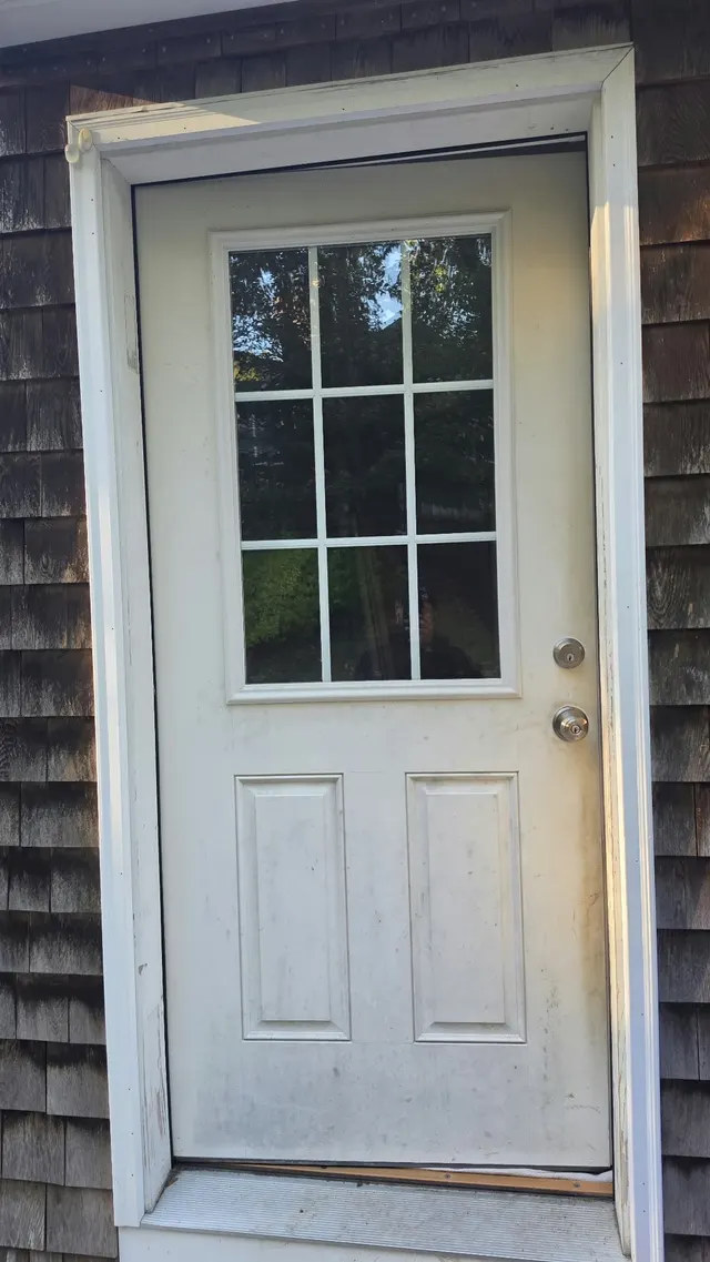 White exterior entry door beside gray shingle siding