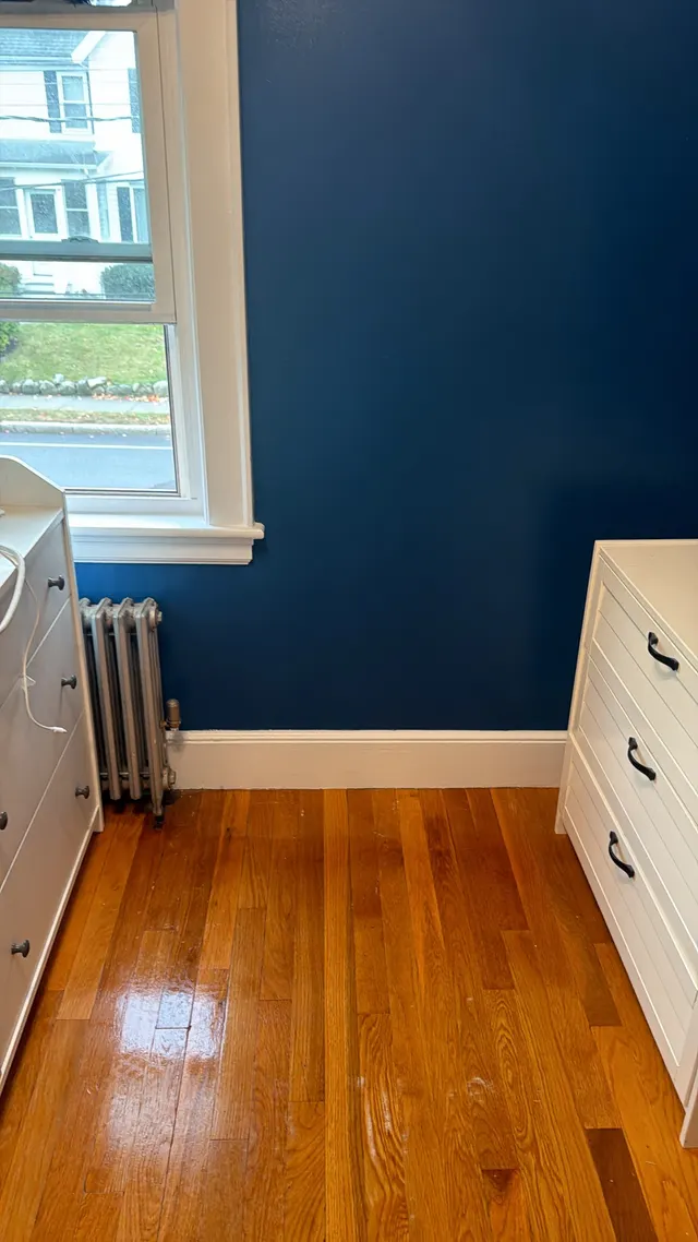 Blue interior wall with white window trim and a radiator